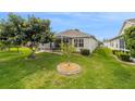 Well-maintained backyard with lush green grass, mature trees, and a screened-in lanai for outdoor relaxation at 17959 Se 89Th Natchez Ave, The Villages, FL 32162