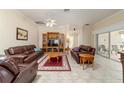 Inviting living room with tile flooring, ceiling fan, comfortable leather furniture, and access to the lanai at 17959 Se 89Th Natchez Ave, The Villages, FL 32162