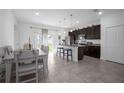 Open-concept kitchen with dark cabinets, granite counters, and dining area with tile floors at 3352 Sw 127Th Lane Rd, Ocala, FL 34473