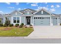 Charming one-story home with a well-manicured lawn and beautiful blue and gray color palette at 4384 Pezzullo Cir, The Villages, FL 32163