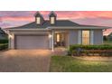 Charming single-story home featuring a two-car garage, brick-paved driveway, and manicured landscaping at sunset at 5111 Nw 35Th Pl, Ocala, FL 34482