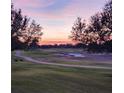 Scenic view of the manicured golf course with sand trap and path, framed by trees at sunset at 5111 Nw 35Th Pl, Ocala, FL 34482