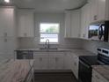 Well-equipped kitchen with white cabinets, granite countertops, stainless appliances, and a tiled backsplash at 9455 Se 152Nd Pl, Summerfield, FL 34491