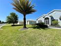 Well-manicured lawn with a large palm tree in front of the light-blue single-story home at 15702 Sw 16Th Avenue Rd, Ocala, FL 34473