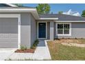Close-up of a home's front facade, showcasing a blue front door, gray siding, and a small garden at 2 Hemlock Ter Dr, Ocala, FL 34472