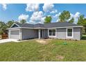 Inviting single-story home with a gray exterior, a well-manicured lawn, and a paved driveway at 2 Hemlock Ter Dr, Ocala, FL 34472