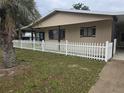 Home exterior showing well-maintained lawn and charming white picket fence near trees at 10040 Sw 98Th Ave, Ocala, FL 34481
