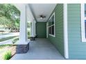 Inviting front porch with stone pillars, ceiling fan, and green siding at 2735 Se 19Th Ct, Ocala, FL 34471