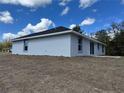 Exterior shot of home, showing stucco siding, dark roof, and side windows at 64 Olive Cir, Ocala, FL 34472