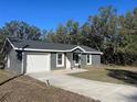 Charming single-story home featuring a one-car garage and a spacious concrete driveway at 74 Fisher Terrace, Ocklawaha, FL 32179