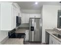 Well-equipped kitchen with stainless steel appliances, granite countertops, and white cabinets at 74 Fisher Terrace, Ocklawaha, FL 32179