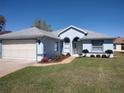Single-story home with a light blue exterior, grey roof, landscaping, and an attached two-car garage at 7407 Sw 112Th Pl, Ocala, FL 34476