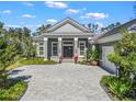 The home's inviting facade features a patterned driveway, lush landscaping, and double front doors at 8033 Nw 28Th St, Ocala, FL 34482