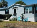 Quaint single-story home features light blue siding, black shutters and colorful landscaping at 8106 County Road 109, Lady Lake, FL 32159