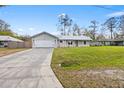 Exterior view of a one-story home with a large driveway, garage, and well-maintained lawn at 12453 Se 61St Ct, Belleview, FL 34420
