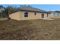 Back exterior view of tan one-story home with sliding glass doors and a small patio at 13 Locust Trak, Ocala, FL 34472