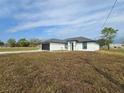A cozy, single-story house boasting a black garage door, white walls, and expansive green lawn at 17 Laurel Pass Ln, Ocala, FL 34480