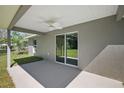 Covered patio featuring gray concrete floor and ceiling fan, extending to the backyard with sliding glass door at 217 Oak Lane Cir, Ocala, FL 34472