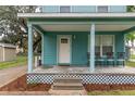 Inviting front porch featuring light blue exterior siding, seating, and lattice detailing around the base at 307 Nw 10Th Ave, Ocala, FL 34475