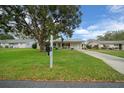 Well-manicured front yard with a charming single-story home, featuring a cozy front porch and attached garage at 6385 Sw 61St Ct, Ocala, FL 34474