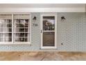 Home's painted brick front facade has a storm door and sconce lighting flanking the front door at 736 Ne 26 Ter, Ocala, FL 34470