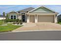 Charming home featuring a well-manicured lawn, detailed landscaping, and a spacious two-car garage with a custom driveway design at 5766 Henry Loop, The Villages, FL 32163