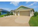 Charming home featuring a well-manicured lawn, detailed landscaping, and a spacious two-car garage with a custom driveway design at 5766 Henry Loop, The Villages, FL 32163