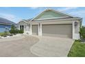 A spacious three-car garage with a decorative concrete driveway and lush landscaping at 5766 Henry Loop, The Villages, FL 32163