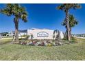 Community entrance sign for Will Villas with palm trees and colorful flowerbed on a sunny day at 7014 Elaine Ct, The Villages, FL 34762