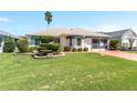 Well-maintained home features lush landscaping with manicured bushes, a vibrant lawn, and painted driveway at 1913 Augustine Dr, The Villages, FL 32159