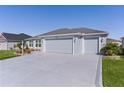 Two-car garage home featuring a concrete driveway and lush green lawn at 6877 Minchew Cir, The Villages, FL 34762