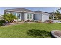 Well-manicured lawn and landscaped flowerbeds enhance the curb appeal of this charming single-story home at 6877 Minchew Cir, The Villages, FL 34762