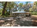 Charming single-story home with mature trees, a long driveway, attached garage, and light gray paint color at 14100 Ne 40Th Ct, Anthony, FL 32617