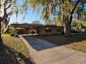 Inviting single-story brick home showcasing an extensive driveway and carport, surrounded by a well-maintained front yard at 911 Oak Dr, Leesburg, FL 34748