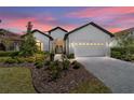 Stunning single-story home featuring manicured landscaping, a paver driveway, and a two-car garage at sunset at 9307 San Jose Blvd, Howey In The Hills, FL 34737