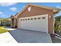 Two-car garage attached to tan house with an extended driveway at 1201 Creekview Ct, St Cloud, FL 34772