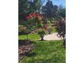 Landscaped yard featuring lush green grass, blooming plants, and a brick paver walkway leading to a serene garden setting at 9230 Sw 66Th Loop, Ocala, FL 34481