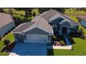 Aerial view of a well-maintained property featuring lush lawn, mature trees, and a beautifully patterned driveway at 13968 Se 96Th Cir, Summerfield, FL 34491