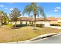 Single-story home featuring an attached two-car garage, complemented by mature trees and a nicely kept lawn at 12240 Se 172Nd Ln, Summerfield, FL 34491