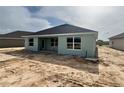Back exterior of home featuring large windows, completed construction with tire tracks in the backyard at 4504 Sw 90Th Lane Rd, Ocala, FL 34476