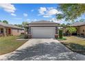 Home exterior featuring a two-car garage, manicured landscaping, and a spacious driveway with a sidewalk at 7665 Sw 96Th Avenue Rd, Ocala, FL 34481