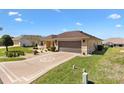 Landscaped front yard leading to a well-maintained home with a two-car garage and driveway at 17472 Se 112Th Ct, Summerfield, FL 34491