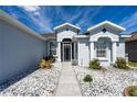 Inviting front entrance featuring a decorative glass door with white rock landscaping and lush greenery at 1813 Sw 157Th Place Rd, Ocala, FL 34473