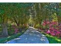 Picturesque driveway lined with lush greenery and vibrant pink flowers, leading to a serene property at 2881 Se 41St Pl, Ocala, FL 34480