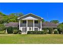 Classic two-story home with white columns, shutters, mature landscaping, and a welcoming front yard at 2881 Se 41St Pl, Ocala, FL 34480