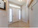 Bright entryway featuring neutral tile, a front door with sidelights, and storage hooks at 5001 Sw 91St Pl, Ocala, FL 34476