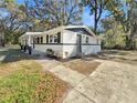 Corner view of a minimalist single-story home with gray door, black shutters, and minimalist landscaping at 5311 Nw 27Th Ave, Ocala, FL 34475