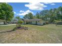 The exterior of a single-story home, has a well-kept lawn with mature trees and shrubs, and a two-car garage at 9300 Se 161St St, Summerfield, FL 34491