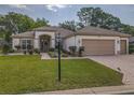 Well-maintained single-story home featuring a brick driveway and lush landscaping at 9509 Se 124Th Loop, Summerfield, FL 34491