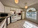 Bright kitchen with white cabinets, tiled floors, and a large window providing natural light at 3617 Westland Dr, Orlando, FL 32818